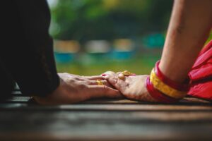 Manos de una pareja tradicional en Nepal con joyas nupciales, simbolizando el matrimonio infantil en contextos culturales.