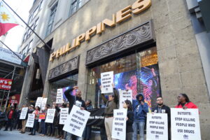 Manifestación contra la guerra contra el narcotráfico en Filipinas frente a una sede oficial, con pancartas que exigen justicia por las muertes causadas por la política antidrogas de Duterte.